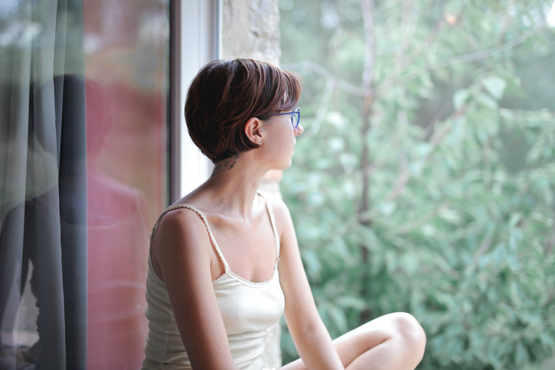 young woman gazing out the window into a natural landscape